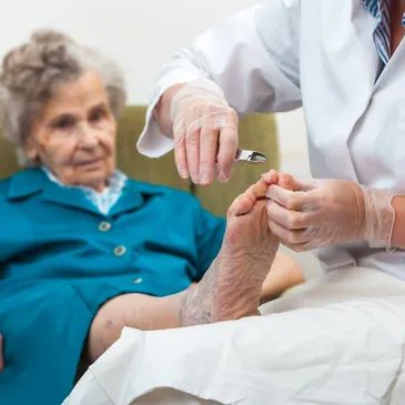 Caregiver providing foot care to elderly woman.
