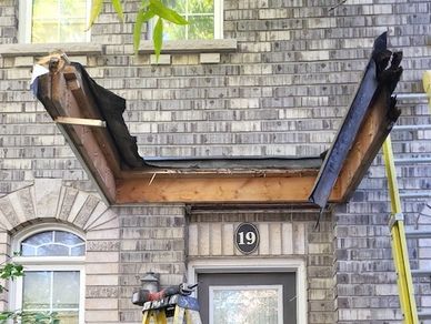 Rotted porch roof framing exposed after demolition. Water damage is evident on corners of framing. 