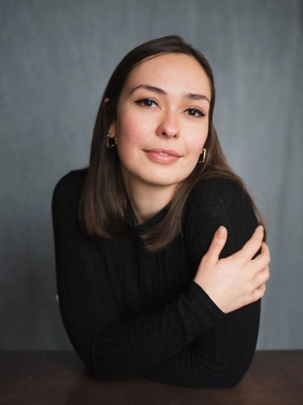 Young woman with brown hair wearing black top.