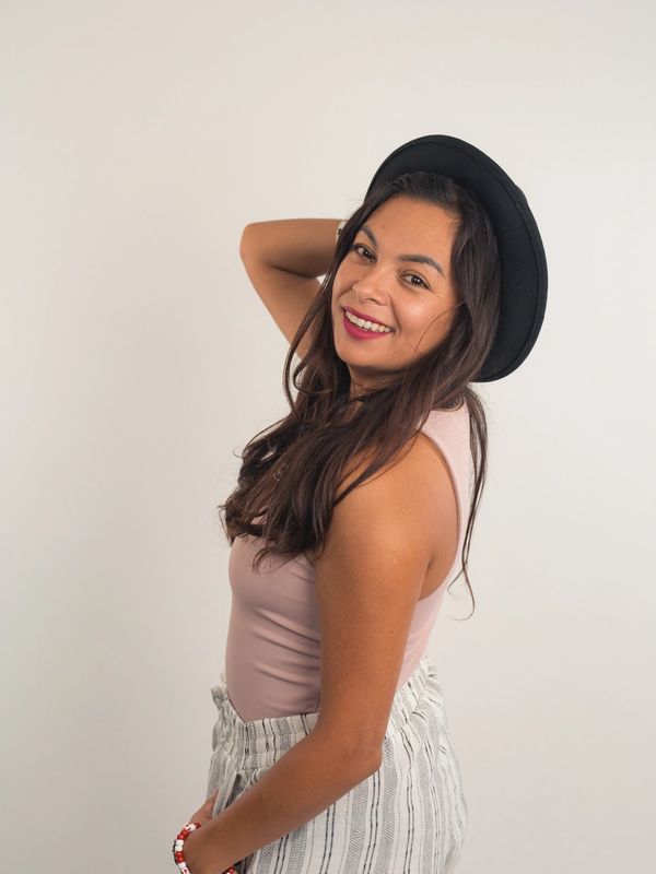 Solo picture of Stephanie Galvez in a pink top, white striped bottom and black hat