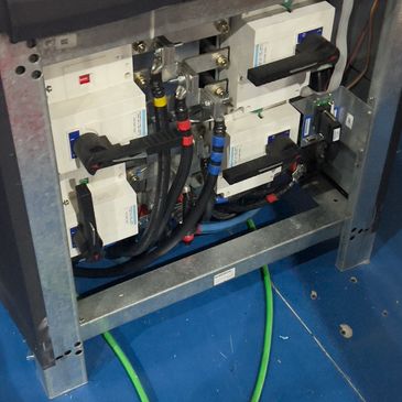 Electrical circuit breakers with colored cables inside a metal frame.