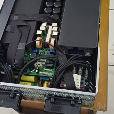 Open electronic device showing internal circuit boards and components on a wooden table.