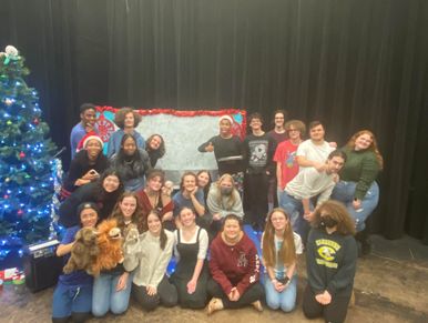 Group photo of diverse young people with Christmas tree and holiday decorations.