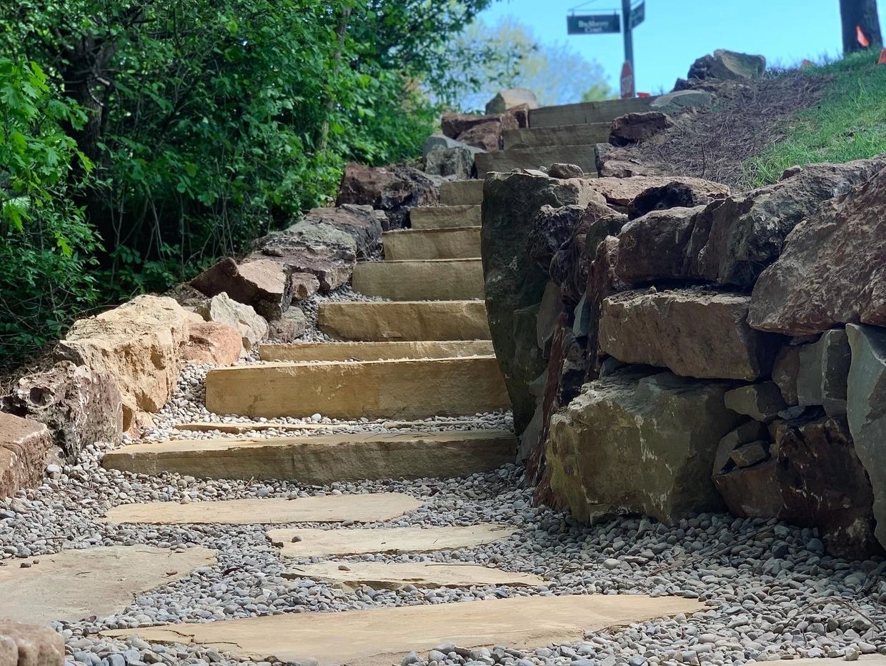 Stone steps with boulder retaining wall, pea gravel pathway, and flagstone stepping stones.