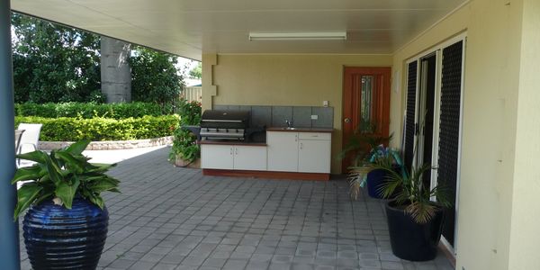 Covered patio with outdoor kitchen and potted plants.