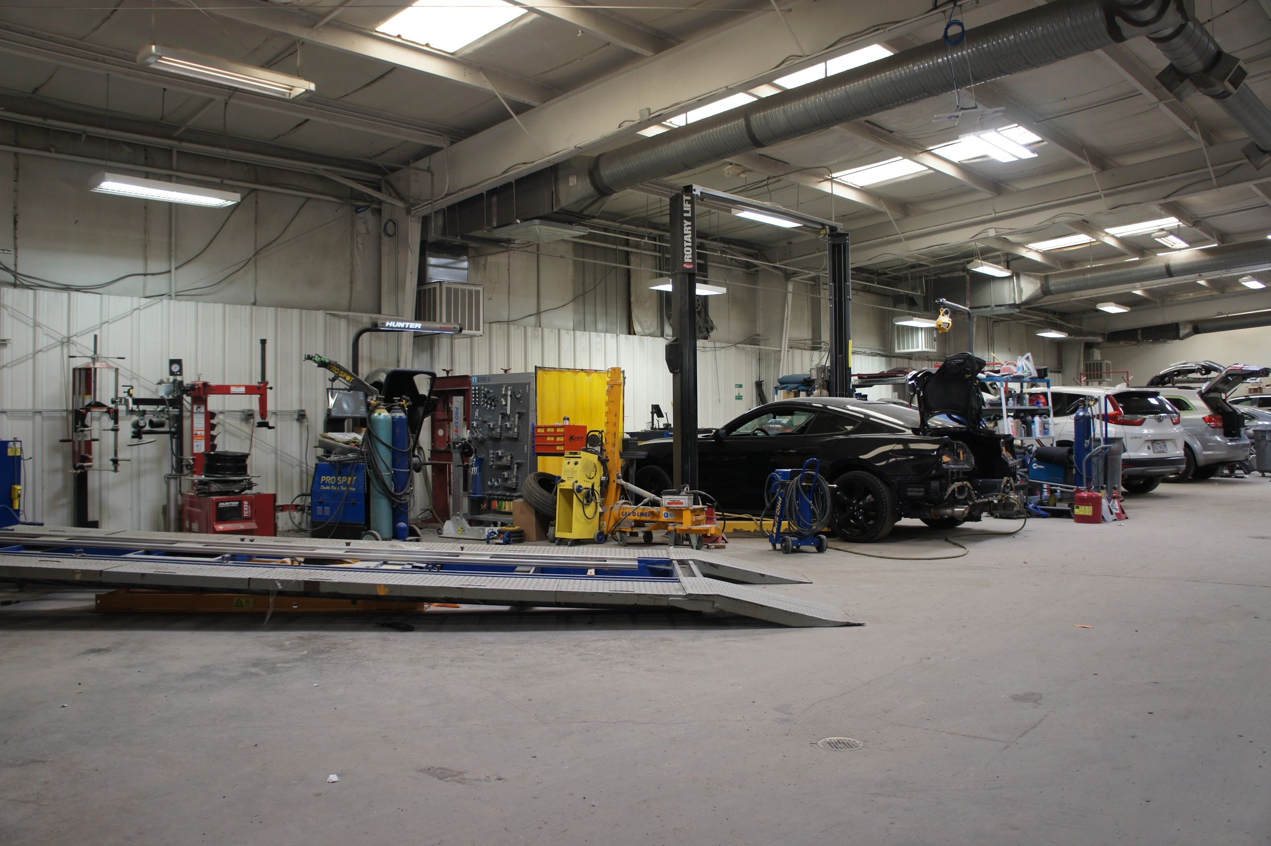 Spacious automotive repair shop with multiple cars and equipment.