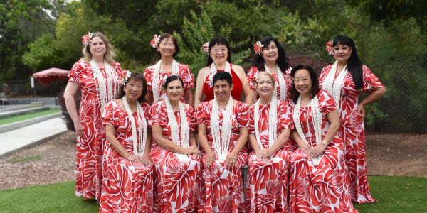 Group of women in matching red and white dresses with leis.