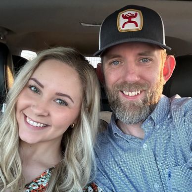 Smiling couple taking a selfie inside a car.
