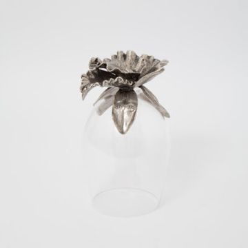 Glass cup with decorative metal flower on top.
