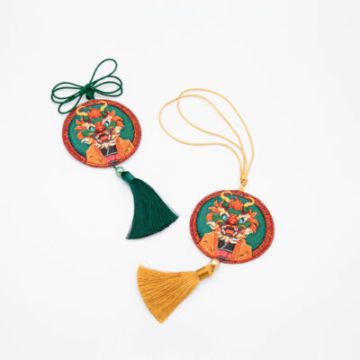 Two circular embroidered keychains with tassels.