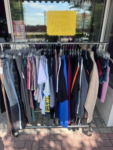 Clothing rack outside store with $10 sale sign on window.