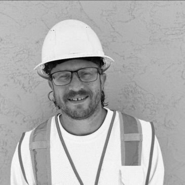 Smiling construction worker wearing a hard hat and safety vest.