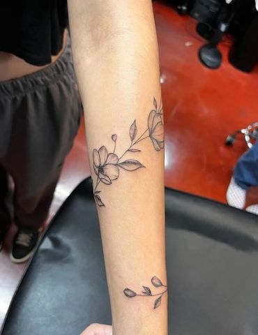 Black line art floral vine on forearm.