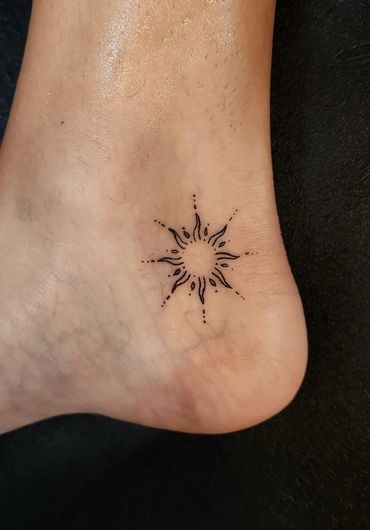 Small minimalist sun tattoo on ankle.