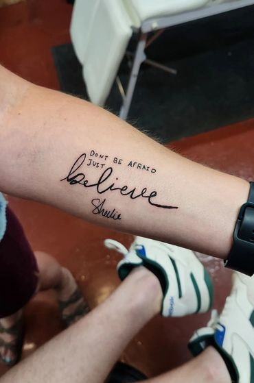 "Believe" script tattoo on forearm.