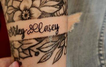 Script name with floral band tattoo.