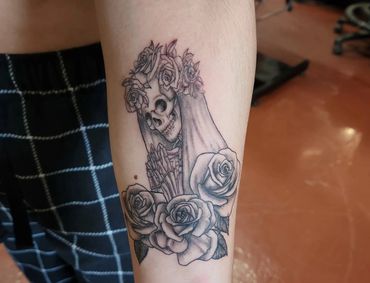 Skull with floral headpiece tattoo.