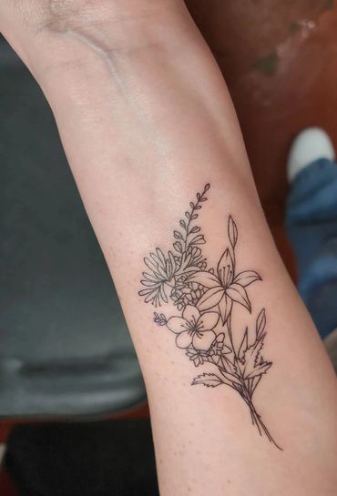 Fine line botanical bouquet tattoo.