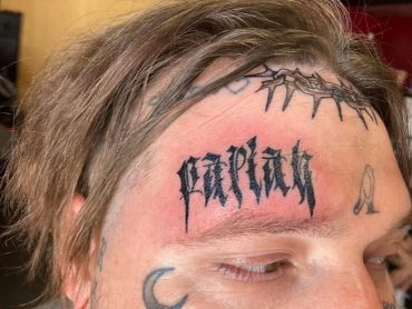 Man with multiple face tattoos including 'Путин'.