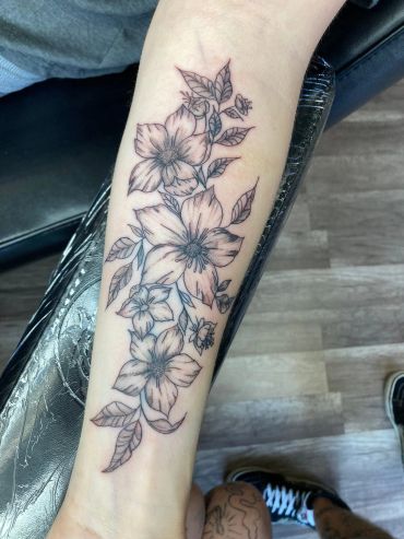 Black ink floral tattoo on forearm.