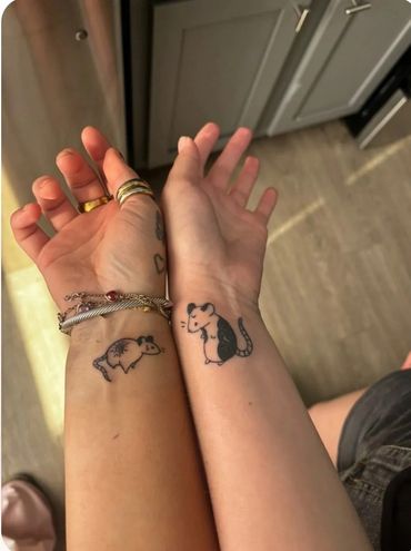 Matching wrist tattoos of small animals.