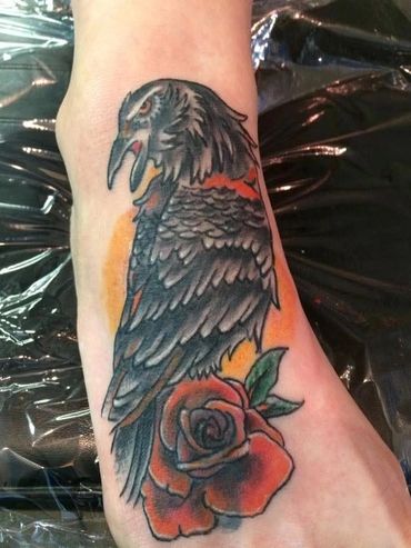 Raven perched on a rose tattoo.