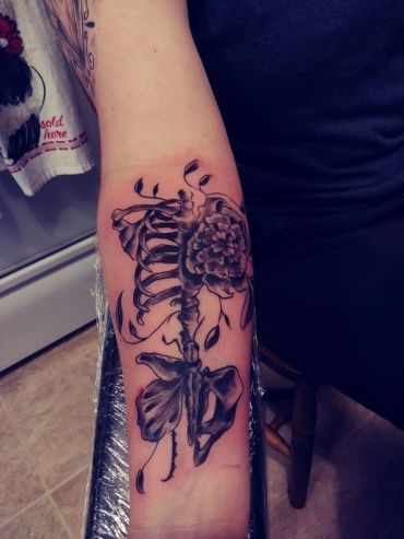 Skeleton torso and roses arm tattoo.