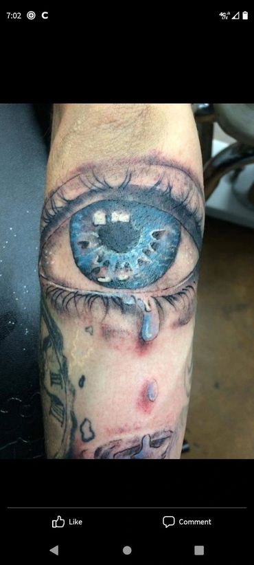 Realistic blue eye with blood tattoo.