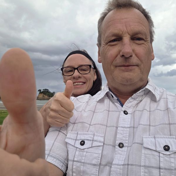 Couple giving thumbs up outdoors.