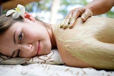 Woman receiving a relaxing spa body treatment with a flower in her hair.