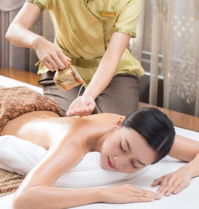 A woman receives an arm massage with oil in a serene spa setting.