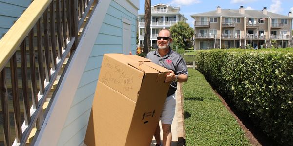 Man carrying a large cardboard box outdoors.