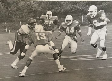 Black and white photo of a football play with players in action on the field.