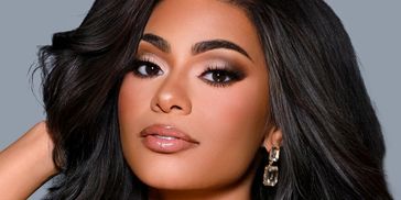 Glamorous woman with voluminous black hair and shimmering silver dress.