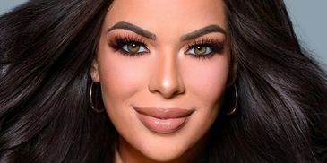 Close-up portrait of a woman with flowing dark hair and striking makeup.