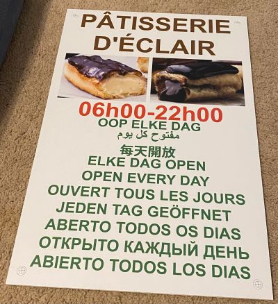 Multilingual sign for a patisserie open daily from 06:00 to 22:00.