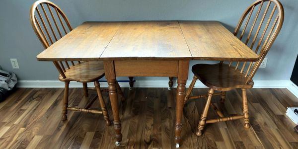 Wooden table with two matching chairs on a wooden floor.