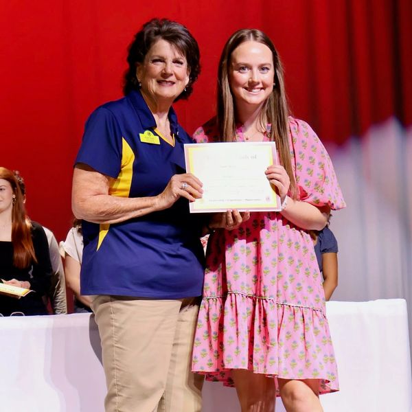 Two women holding a certificate on stage.