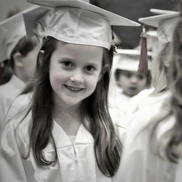 Young girl in graduation gown and cap smiling.