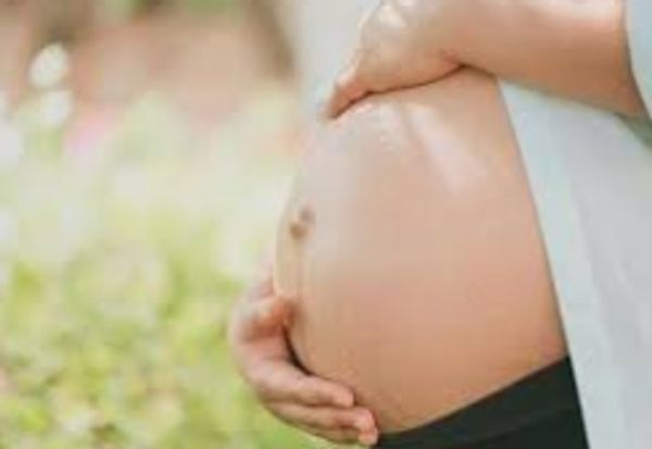 Close-up of a pregnant woman's belly and a smiling infant.
