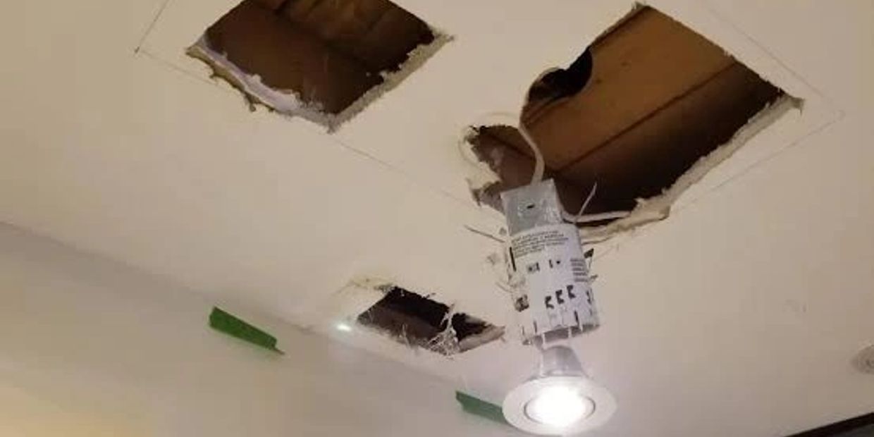 Ceiling with exposed holes and a hanging light fixture.