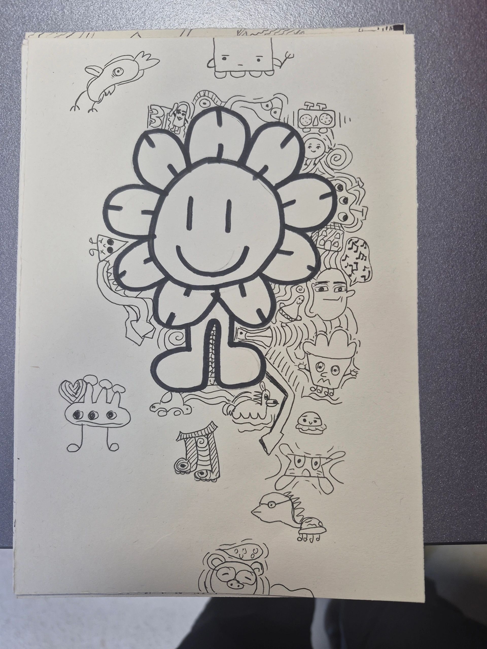 A large smiling flower surrounded by various quirky doodles on paper.
