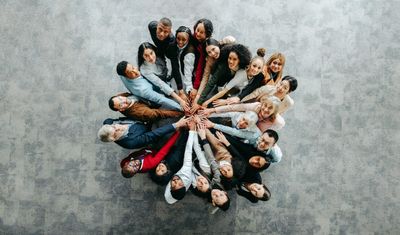 Grupo diverso de personas uniendo manos en círculo.