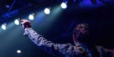 Worship leader lifting hands in praise during service.