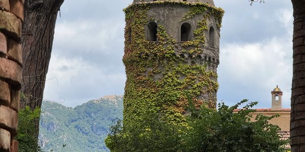 Ancient ivy-covered stone tower set against a mountainous backdrop.