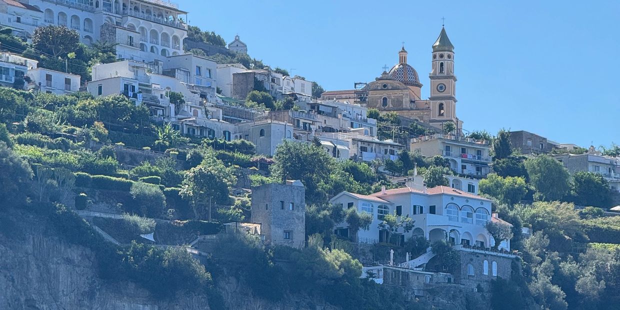 Picturesque hillside town with white buildings and a church tower under clear blue sky.