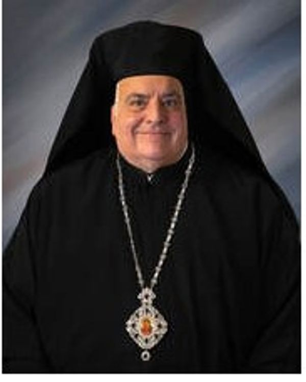 Clergy member in traditional religious attire with a large pendant necklace.