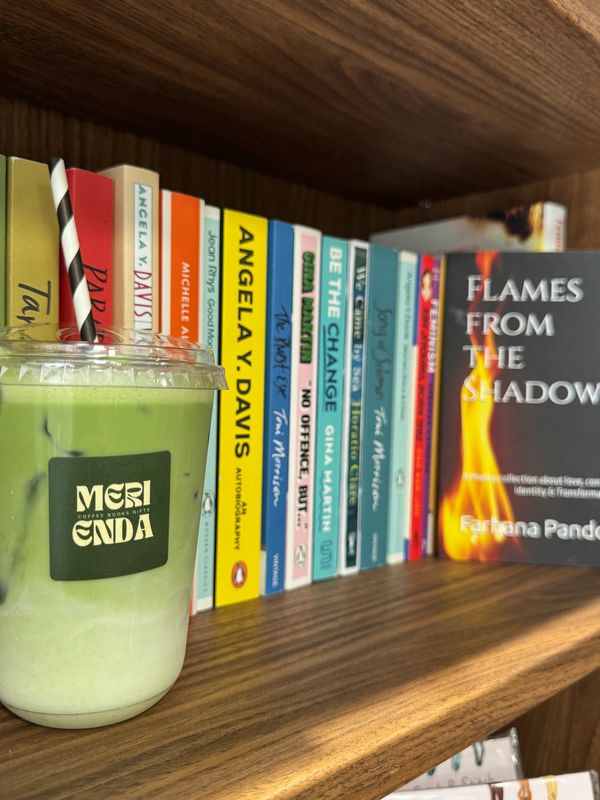 Green iced drink with books on a wooden shelf.
