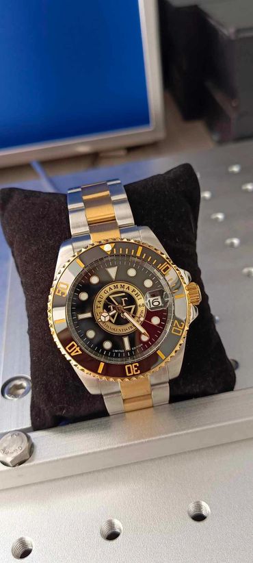 Luxury wristwatch with gold and silver band on a black cushion.