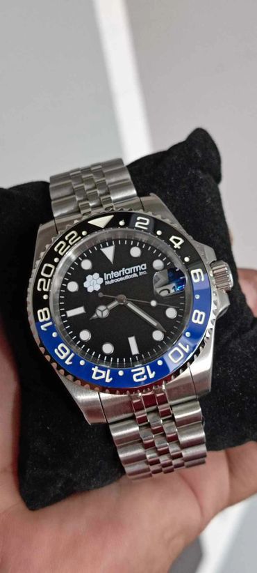Stainless steel wristwatch with black and blue bezel and Interfarma branding.